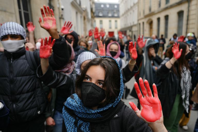 Protesters display mock blood on their hands as they take part in a demonstration in front of the Institute of Political Studies (Sciences Po Paris) occupied by students, in support of Palestinians, in Paris on April 26, 2024. - Students occupied a new building at Sciences Po Paris, in support of Palestinians, a day after police evacuated another of the school's sites, echoing protest action at American universities. (Photo by Dimitar DILKOFF / AFP)