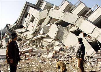 مواطنون ينظرون إلى الدمار الذي لحق بإحدى العمارات في بلدة كاي قرب مدينة أفيون التركية إثر الزلزال الذي ضرب المنطقة هناك