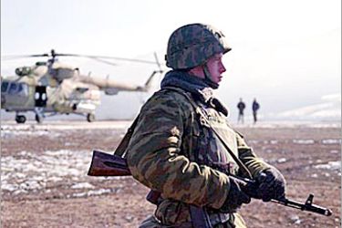 A Russian soldier stands guard in front of a military helicopter