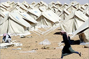 A Jordanian runs in front of a tent camp, managed by the Hashemite Charitable Organisation with the help of the United Nations High Commissioner for Refugees (UNHCR), in Rweished some 60 km (38 miles) from the Iraqi-Jordanian border, March 22, 2003. The tents are being erected for any Iraqis who might flee the country after the United States launched a war to disarm Iraq, but no Iraqis have yet arrived the camp. REUTERS/Wolfgang Rattay