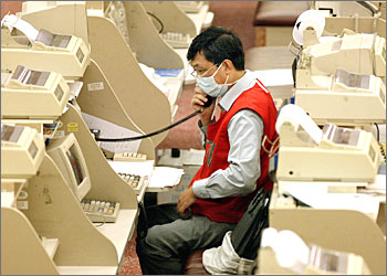 A trader wears a mask at the Hong Kong Stock Exchange to protect against SARS as the key Heng Seng gains 3.67 percent, 29 April 2003. The index gained 309.18 points to close at 8,744.22, boosted by overnight gains on Wall Street and the World Health Organisation's (WHO) comments that Severe Acute Respiratory Syndrome (SARS) appears to have peaked in the territory, dealers said. AFP PHOTO/Peter PARKS