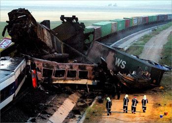 Firemen stand beside mangled wreckage and derailed carriages of a goods and passenger train that crashed near Spain's southeastern village of Albacete June 4, 2003. The crash killed five people state railway company RENFE said on Wednesday and 20 people were missing after the crash. REUTERS/Sergio Perez