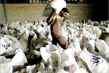 f - An Iraqi worker prepares to load bags of wheat onto a truck at a storehouse of the World Food Programme,