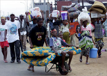 Liberian civilians carrying their belongings flee as rebels move closer toward the capital Monrovia July 19 2003. Thousands of residents fled from the neighbourhoods in the northwestern districts towards the centre of Monrovia on Saturday, fearing a fresh rebel assault on the city after rebels smashed through a key line of defence, witnesses said. REUTERS/Luc Gnago