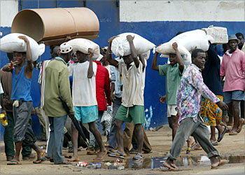 Hungry Liberians carry sacks of food after they stormed into Monrovia's port to grab food August 13, 2003 as rebel fighters packed up to hand it over to U.S.-backed West African