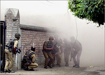 Indian Border security force personnels take cover as dust and smoke raises after troops blasted a house in downtown Srinagar, 30 August 2003, following a gunbattle with alleged Kashmiri millitants. At least four Islamic rebels and an Indian soldier died during a gunbattle which ensued when troops raided a Kashmir building they believed housed a mastermind of the 2001 attack on India's parliament. AFP PHOTO/TAUSEEF MUSTAFA