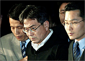 South Korean-born Song Du-yul (C), a sociologist who is now a German citizen, is taken away by unidentified prosecuters at the prosecutor's office in Seoul October 22, 2003. Prosecutors executed an arrest warrant for Song on charges of violating South Korea's anti-communist National Security Law. Song, a philosophy professor at Muenster University in Germany, returned to his native country on September 22 after 37 years of self-imposed exile. REUTERS/Kim Kyung-Hoon