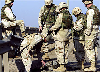 F_US soldiers inspect a crater in the ground caused by an improvised explosive device (IED) attack on a US military convoy early 05 December 2003 in Baghadad. "Two bomb attacks hit US convoys in Baghdad Friday morning", a US military spokesman said, adding that there was no immediate word on casualties. "We can confirm that at least two improvised explosive devices (IED) of the sort favoured by anti-US insurgents exploded in Baghdad," the spokesman said. AFP PHOTO/Cris BOURONCLE