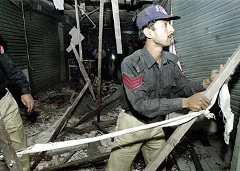 f: A Pakistani policeman inspects a blast site in a shopping centre of the southern port city Karachi