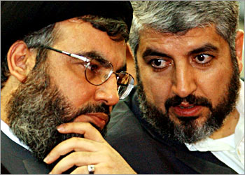 Lebanons Hizbollah leader Sheikh Hassan Nasrallah (L) talks to Lebanons Palestinian Hamas leader Khaled Meshaal (R) during a rally in Beirut March 27, 2004. Nasrallah told thousands of suppoters gathered at a memorial service for assassinated Hamas spiritual leader Sheikh Ahmed Yassin, that Hamas could consider Hizbollah under its command. REUTERS/Mohamed Azakir