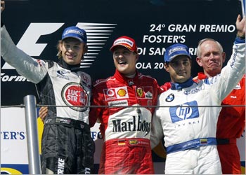 f: English BAR-Honda driver Jenson Button (L), German Ferrari driver Michael Schumacher (C), and Columbian BMW-Williams driver Juan Pablo Montoya pose on the podium of the Imola racetrack after the San Marino Grand Prix,