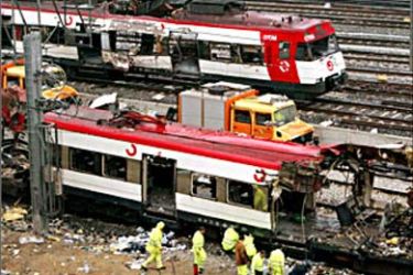 f - Railway workers remove debris from the wreckage of a bombed public train as a second destroyed train is pulled out of Atocha train station in Madrid, March
