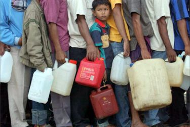A young Indonesian boy waits to buy gasoline in a long line as people have been waiting for three days at a petrol station near Banda Aceh, Indonesia, 30 December 2004.