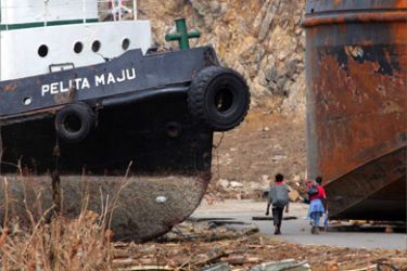 Indonesian men walk past ships beached 100m (109 yards) onto shore in Lhoknga district,