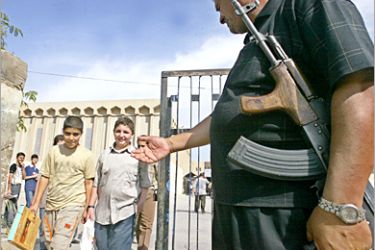 AFP - A security officer guards a school as children arrive to sit their end of year exams in the Muhandiseen neighbourhood of Baghdad 19 May 2005. Students across this war-torn