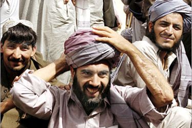 AFP - Former Afghan prisoners smile as they try on turbans in Kabul, 02 July 2005, after being released from custody by US authorities. Some 57 Afghan prisoners have been released