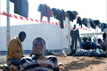 AFP / Recently arrived African immigrants lie exhausted by the temporary immigrant housing centre after crossing the double fence between Morocco and the Spanish enclave