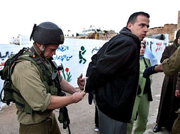 epa00567822 An Israeli soldier ties plastic handcuffs on a Palestinian man in the West Bank city of Hebron on Friday, 04 November 2005 as the man is arrested and two