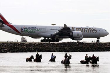 r_Strappers and stable hands exercise thoroughbred race horses in Botany Bay as an Emirates Air passenger jet taxis before takeoff at Sydney Airport November 29, 2005. Emirates Air sponsors Australasia's richest horse race, the Melbourne Cup and Worldwide it spends US$200 million a year on corporate communications and sponsorship. REUTERS/Will Burgess