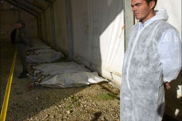 r - A forensic worker stands near bodybags containing the remains of ethnic Albanians killed in Kosovo in 1999 and trucked to a mass grave near the Serbian capital Belgrade