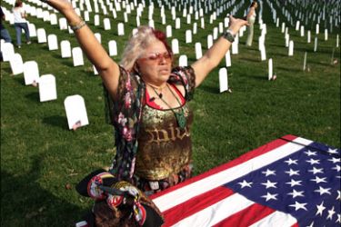 afp - Maria Carrillo, a resident of Miami, prays over a mock coffin in front of makeshift tombs representing fallen US soldiers in Iraq as she participates in an anti-war rally