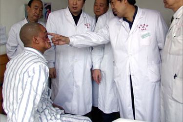 Doctors look at the face of Li Guoxing (L) after he received a face transplant at Xijing hospital in Xian, 14 April 2006. Li a hunter and a native of the Lisu ethnic minority in the southwestern province of Yunnan