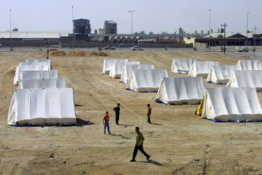 Iraqi Sunnis walk through lines of tents in a newly erected refugee camp,