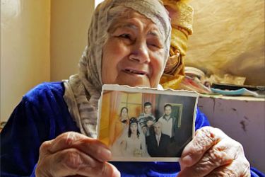 A Palestinian woman shows a picture of her family at her apartment at Baghdad's eastern Baladiat district, 26 March 2006.