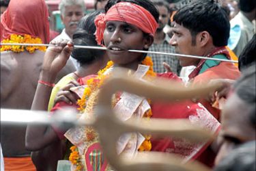 f_A Indian Hindu devotee walks with a steel rod piercing his cheeks as he takes part in a procession held