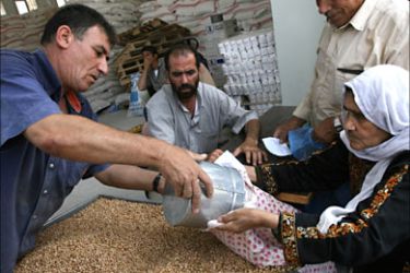 f_A Palestinian women fills a bag with dried chick-peas from the United Nations food aid distribution center for residents in the northern Gaza Strip in the Jabalya refugee camp, 04 July 2006
