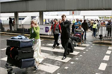 epa00794160 Passengers at London's Heathrow airport leave a marquee tent, ahead of being directed to a check in desk, Sunday, 13 August 2006. Travelers are experiencing