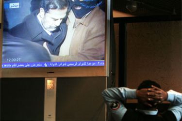 An Iraqi policeman watches a large-screen broadcast of the official video showing Iraqi President Saddam Hussein moments before his execution 30 December 2006, inside the heavily-fortified Green Zonein Baghdad