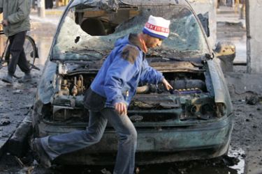 A youth walks past a damaged vehicle after a car bomb attack in Baghdad December 25, 2006. A car bomb killed at least 10 people and wounded 15 when it exploded on a busy