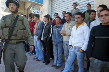 An Israeli soldier stops Palestinian Hebron University students to check their identity cards in the West Bank city of Hebron, 27 January 2007.