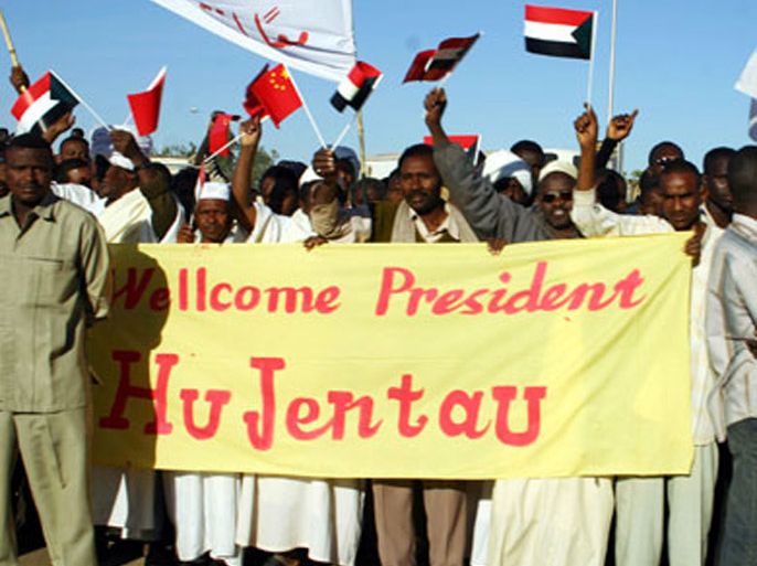Sudanese men wave Chinese and national flags as they welcome Chinese President Hu Jintao on the airport road in Khartoum 02 February 2007. During his two-day visit to Sudan