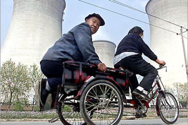 AFP (FILES) This file photo dated 21 April, 1999 shows a wife cycling her husband down a lane next to giant the water-cooling towers of a coal-burning energy plant in the suburbs
