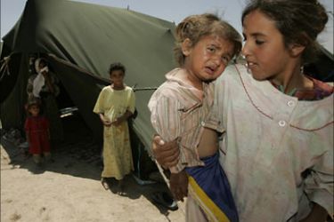 r_Refugees stand outside their tents in a refugee camp in Shaab district in Baghdad June 10, 2007. Dozens of Shi'ite villagers were evacuated by the Red Crescent from