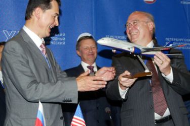 Boeing Vice President Scott Carson hands a model of an airplane to Russian airline Aeroflot Chief Executive Valery Okulov (L) after signing a deal during the International Economic Forum in St. Petersburg