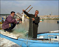 صياد في شريعة الشواكة في كرخ بغداد يصطاد سمكا من نوع كطان (الجزيرة نت) 