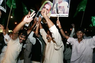 f_Supporters of Pakistani President Pervez Musharraf carry their leader portraits as they dance during a pro-Musharraf rally in front of the President House after a Supreme Court
