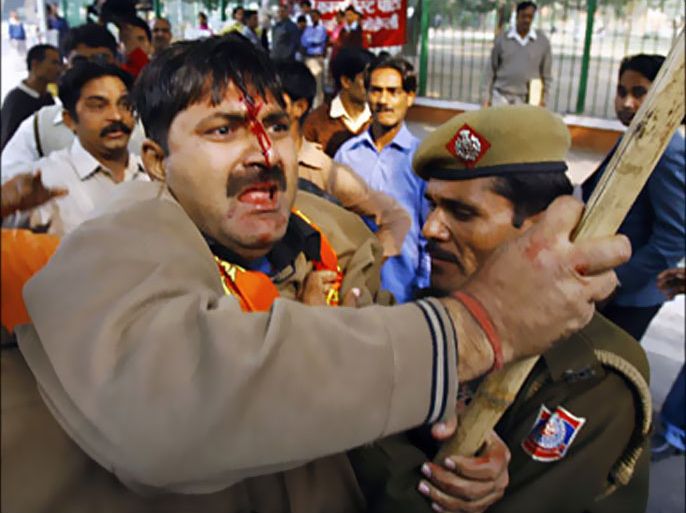 f_Indian Hindu activist (C) his face bloodied after a fight with Muslim rivals is restrained by policemen during a protest in New Delhi, 06 December 2007, on the fifteenth anniversary