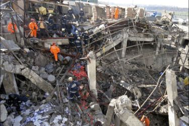 r - Firemen and rescue workers stand on the wreckage of a collapsed building after an explosion in a factory in Istanbul January 31, 2008. An explosion at an Istanbul factory on