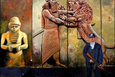 f/An Iraqi policeman stands guard in front of a blast wall featuring paintings, around a building in downtown in Baghdad, 30 January 2007