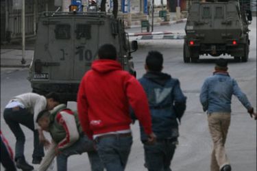 afp - Palestinian youths throw stones at Israeli military vehicles as they withdraw from the centre of the northern West Bank city of Nablus, 05 January 2008