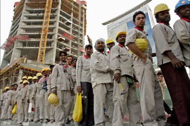 f_Foreign workers stand in line to take a bus that will transport them to where they live at the end of their shift at a construction site in Dubai on April 16, 2008.