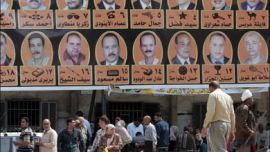 afp - Egyptians walks under a huge poster for candidates for local elections in the al-Mataryah district of Cairo on April 8, 2008. Egyptians were voting on April 8, 2008 in a municipal