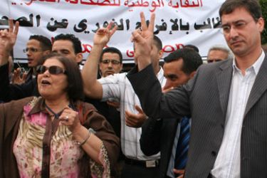 Head of the Moroccan press union (SNPM) Yunes Moujahid (R) is flanked by Moroccan journalists during a protest in front the headquarters of Arab weekly Al Watan to ask