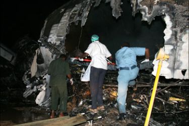 r : Rescue workers examine the scene where a Sudan Airways plane burst into flames after landing at Khartoum airport June 10, 2008. The Sudanese airliner burst into