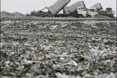R/Dump trucks and a bulldozer shift garbage at the Outer Central Breakwater Landfill Site in Tokyo July 7, 2008. REUTERS/Toru Hanai (JAPAN)