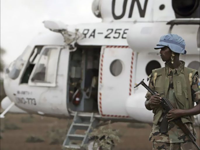 A Rwandan soldier serving with the United Nations-African Union Mission in Darfur (UNAMID) stands guard next to a UN helicopter in the village of Dar es Salam, North Darfur